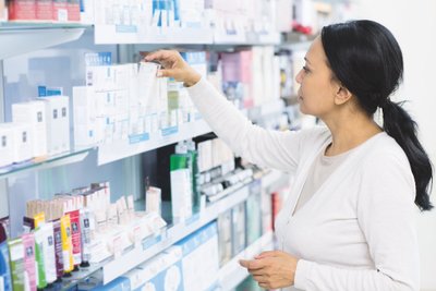 Frau im Einzelhandel vor Regal mit diversen Kosmetikprodukten